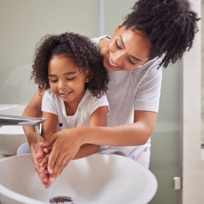 mother and daughter washing hands at sink